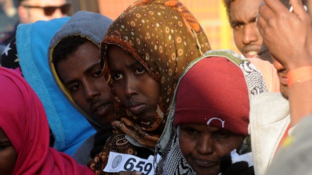 A rescued migrant holds a Gabinetto di Polizia Scientifica number after disembarking from an Italian Coast Guard ship in the harbor of Palermo, Sicily, southern Italy.