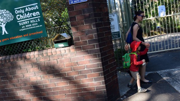 A parent leaves with their child from the Only About Children Childcare centre in Surry Hills where a member of staff has been diagnosed with TB.