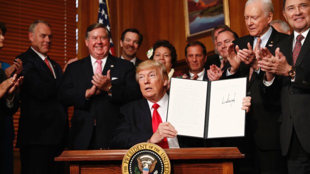 President Donald Trump holds up the signed executive order in Washington on Wednesday.
