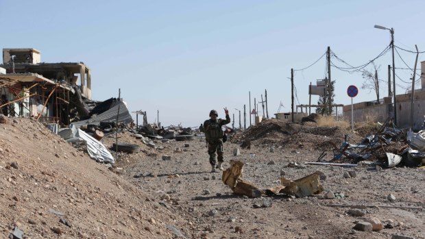 A Kurdish Peshmerga fighter flashes the victory sign as he walks through the town of Sinjar after it was retaken from the Islamic State group on Friday.