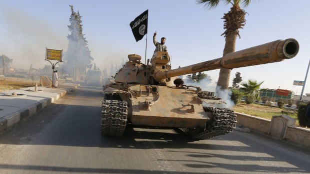 Islamic State fighters ride a tank along the streets of northern Raqqa, Syria. IS militants group executed at least 23 civilians on Friday as they advanced towards Syria's ancient desert metropolis of Palmyra.