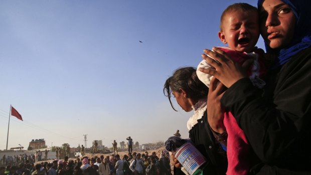 A Syrian refugee holds her baby after crossing into Turkey from Syria in Akcakale.