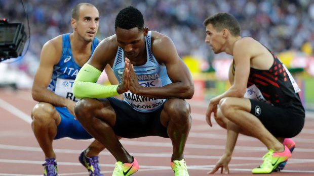 Botswana's Isaac Makwala (centre) prays after winning a 400m semi-final in London. He was barred from the final due to illness.