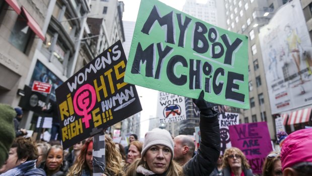 Demonstrators hold signs while marching towards Trump Tower during the Women's March in New York, U.S., on Saturday, January 21, 2017. 