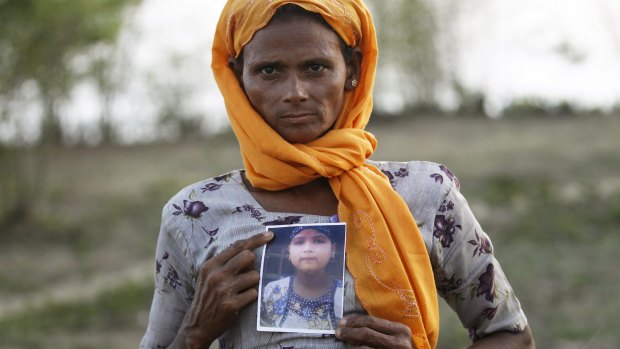 A Rohingya Muslim woman in Myanmar with a picture of her daughter, who she says is being held by a human trafficker.