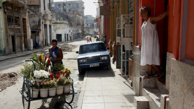 A flower salesman pushes his cart down a street in Havana, Cuba.