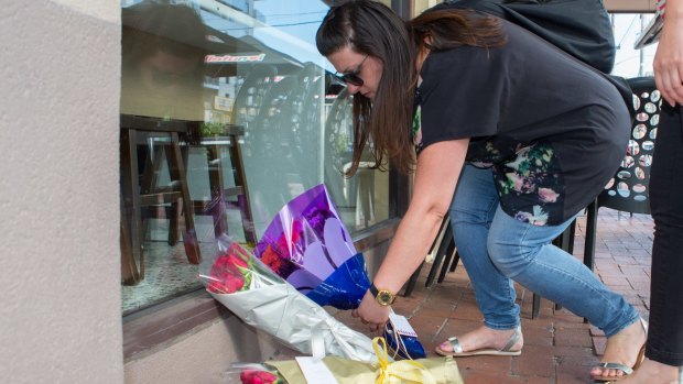 A woman lays flowers at Joseph Acquaro's Gelobar restaurant on Tuesday.
