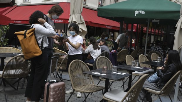 A waitress checks clients' health passes at a restaurant in Paris.