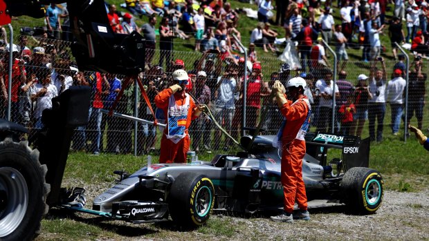 Marshals move the car of Lewis Hamilton of Great Britain and Mercedes after crashing on the first lap of the Circuit de Catalunya in Montmelo.