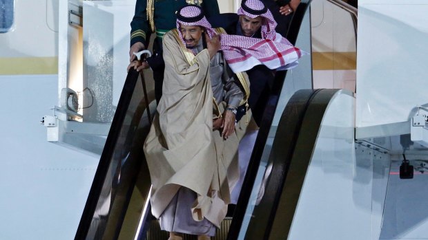 Saudi Arabia's King Salman bin Abdulaziz Al Saud carefully makes his way down the golden escalator.