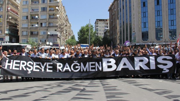 People holding a banner that reads ''Peace despite everything'' march to the site of the attack.