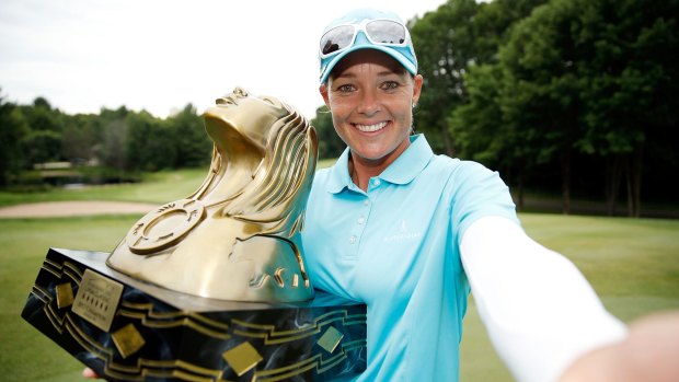 Katherine Kirk  imitates a "selfie" as she poses with the championship trophy after winning the Thornberry Creek LPGA Classic.