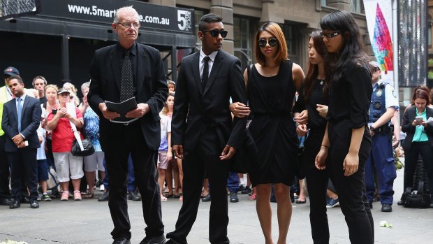 Siege survivors Joel Herat (second from left), Elly Chen (second from right) and Fiona Ma (right) pay their respects at a wreath-laying ceremony after the funeral for Tori Johnson.