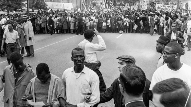 At far left fore is American religious and Civil Rights leader Martin Luther King Jr (1929 - 1968), with Andrew Young in front of him. At left rear is the Dexter Avenue Baptist Church which served as headquarters for King during the Montgomery Bus Boycott (1955 - 1956); King had been Pastor of the church between 1954 to 1960.