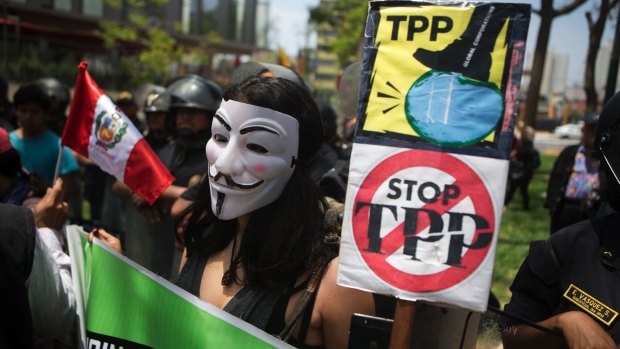 A protester holds signs against the Trans Pacific Partnership during a rally in Lima, Peru, last year.