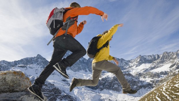 Taking risks: Two hikers jump from a rock onto a snowy slope.