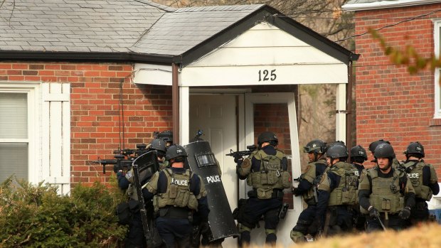 A police tactical team prepares to enter a home on Dade Avenue, in Ferguson, Missouri on Thursday as they search for a suspect in the shooting of two police officers during protests earlier in the day.