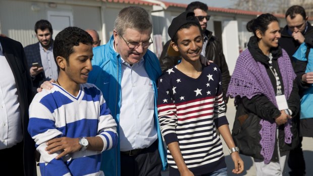 IOC President Thomas Bach (second left) chats with two young refugees during his visit at a refugee camp in Athens.