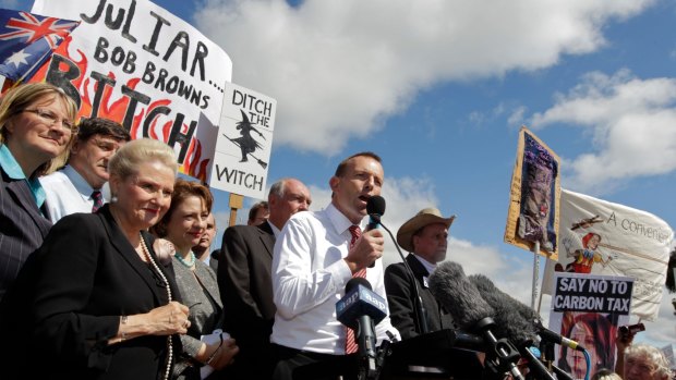 Then opposition leader Tony Abbott in front of a "ditch the witch" poster at a rally outside Parliament House in 2011.