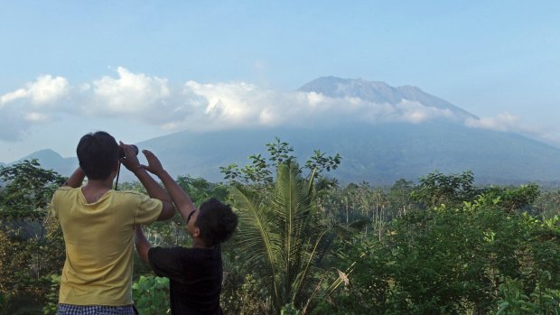 A man observes the Mount Agung with binoculars at a viewing point in Bali, Indonesia.