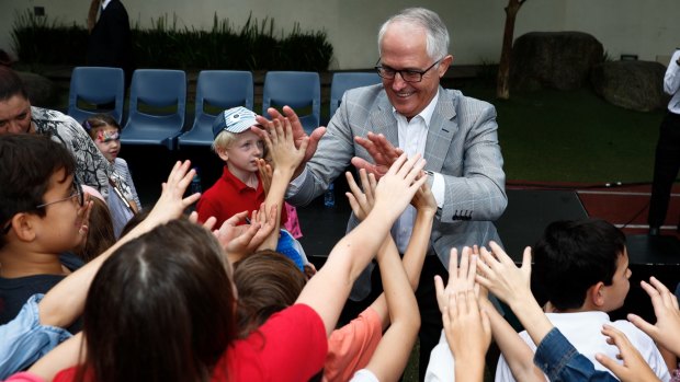 Prime Minister Malcolm Turnbull gives high-fives to children during his visit to the Australian International School in Hong Kong.