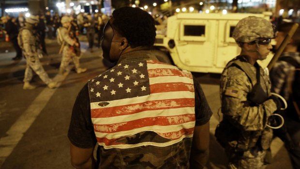 A protester watches soldiers pass as curfew approaches on Friday.