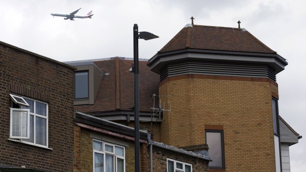 A airliner flies past the offices of notonthehighstreet.com, an online retailer in Richmond, a southwest suburb of London where the body of a suspected stowaway was found on the roof.