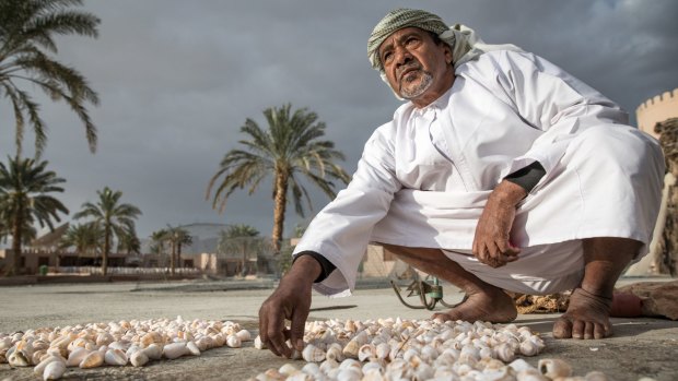 An Omani man laying out sea shells.