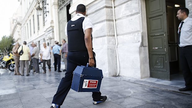 A security guard delivers cash to a National Bank of Greece branch in Athens.