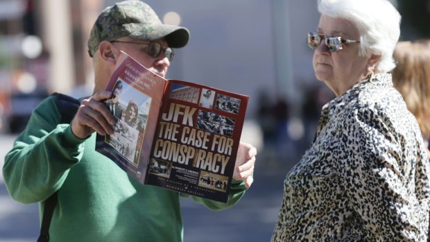 A newsagent in Dealey Plaza, Dallas, shows a magazine to a tourist on Wednesday.