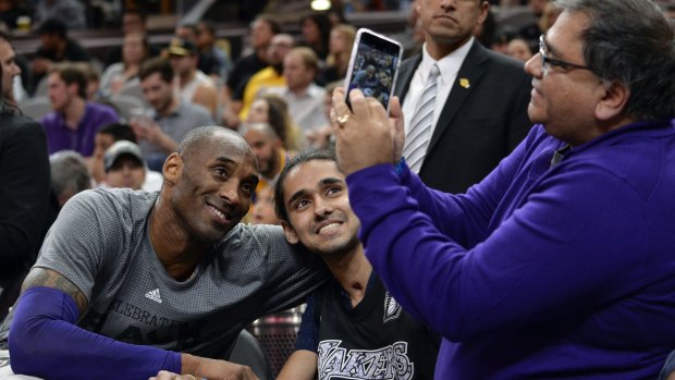 Los Angeles Lakers guard Kobe Bryant poses for a photo with a fan.