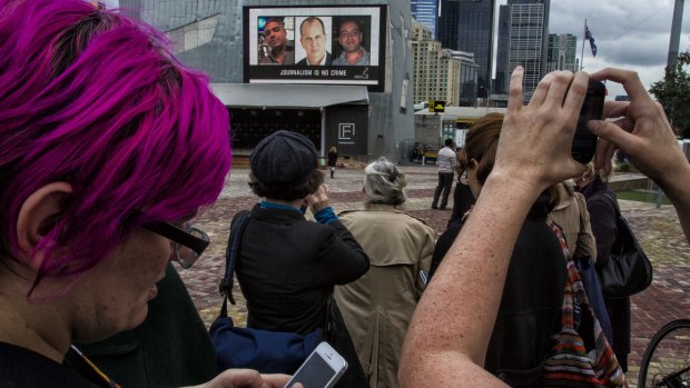 Public rally: People in Federation Square in Melbourne take photos of a TV screen showing jailed Al Jazeera staff. One of those men, Australian Peter Greste, says he has drawn strength from such displays of support.