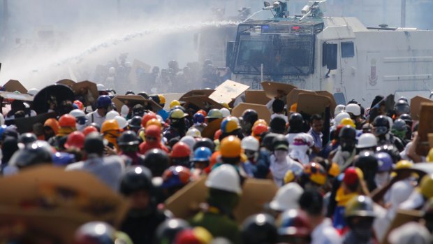 A water canon sprays anti-government protesters as security forces block an opposition march in Caracas on Wednesday.