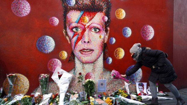 A woman leaves flowers beneath a mural of David Bowie in Brixton, England, in January.