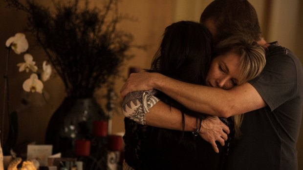 Aaron Short's parents and girlfriend embrace in mourning in front of a shrine in their family home.
