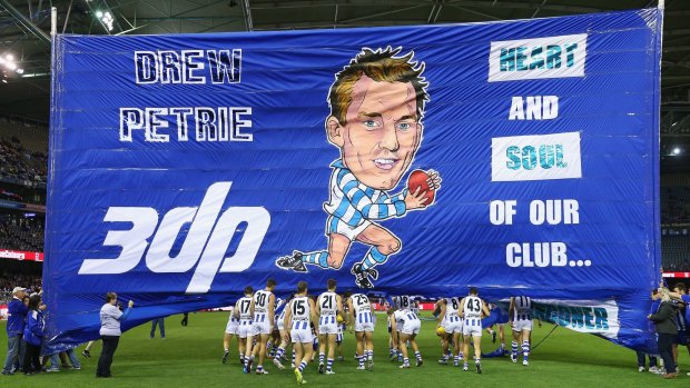 Landmark game: Drew Petrie of the Kangaroos and teammates run through the banner for his 300th match.