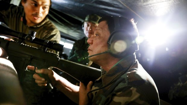 President Rodrigo Duterte holds an assault rifle during a visit to Marawi.