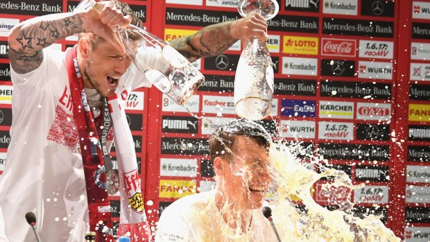 Daniel Ginczek pours beer over VfB Stuttgart coach Hannes Wolf during a press conference after winning Bundesliga promotion.