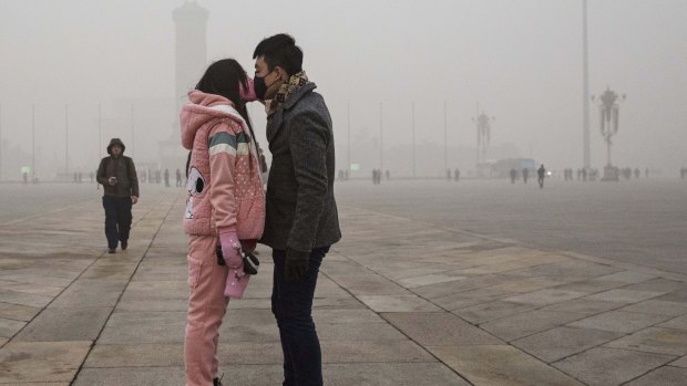 A mask-wearing Chinese couple kiss in Tiananmen Square in Beijing on Tuesday. 