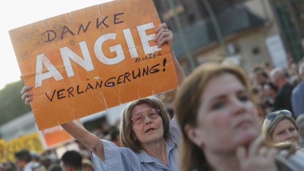 A supporter of  Angela Merkel and her Christian Democrats holds up a sign that reads 'Thanks Angie, keep going!'.
