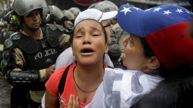 Opponents to Venezuelan President Nicolas Maduro react as fellow demonstrators are arrested.