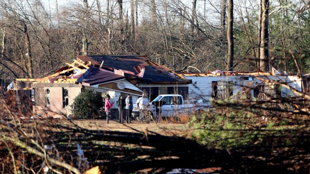 Uprooted trees lay across yards as family and friends gather early Friday morning to offer assistance and support to victims of a tornado that hit Holly Springs.