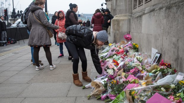 A young woman lays flowers outside the Houses of Parliament following Wednesday's attack on Westminster.
