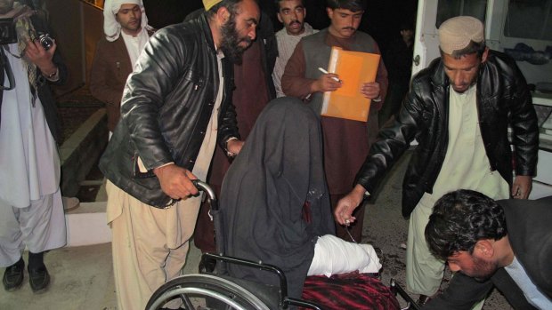 A wounded Afghan woman is taken to hospital after a rocket fired during fighting between Afghan forces and insurgents killed dozens of wedding guests. 