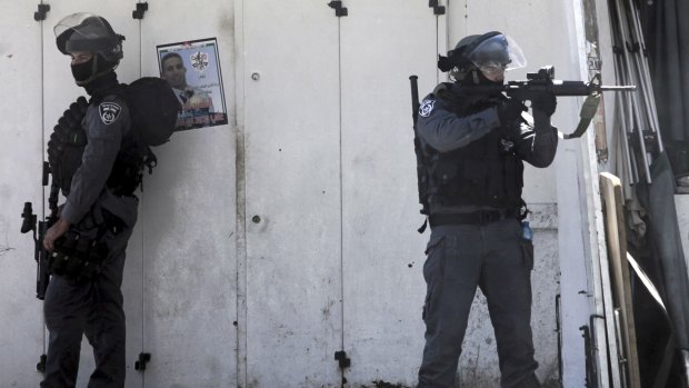 Israeli border police stand next to a poster of Palestinian teenager Ali Abu Ghannam, who was shot dead after allegedly approaching police with a knife at a checkpoint near East Jerusalem.