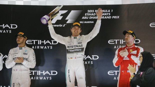 Token applause: Mercedes driver Lewis Hamilton looks unimpressed as Nico Rosberg celebrates his Abu Dhabi Grand Prix win alongside third-placed Ferrari driver Kimi Raikkonen.