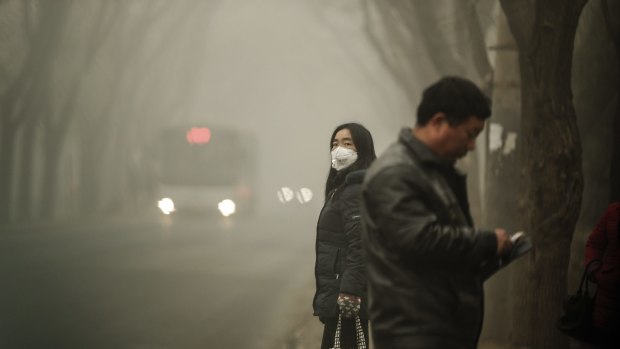 A woman wears a face mask next to traffic shrouded in heavy smog on Tuesday.