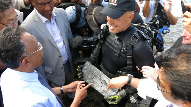 Underwater explorer Barry Clifford, right, presents a silver bar he believes is part of the treasure of the pirate Captain Kidd, to the President of Madagascar, Hery Rajaonarimampianina, left, on Sainte Marie Island.