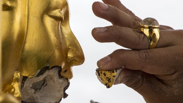 A craftsman fixes the statue of Hindu god Brahma after it was damaged during the deadly blast at the Erawan Shrine.