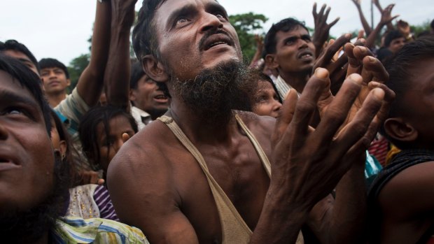 A Rohingya man stretches his arms out for food distributed by local volunteers
